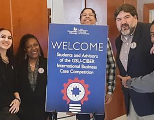 Students holding sign and pointing at it 